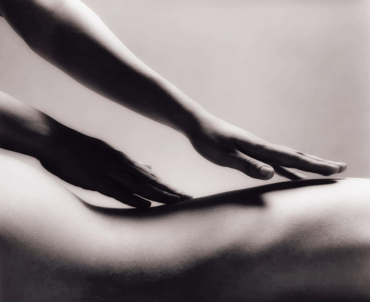 Black and white photo of hands giving a sensual massage on bare skin