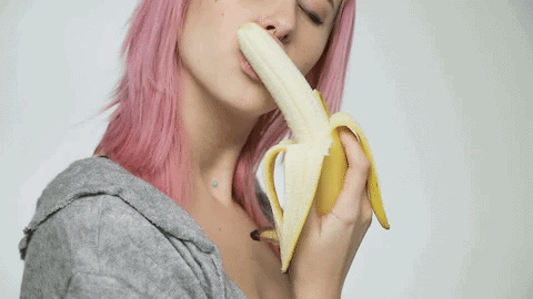 Woman with pink hair suggestively eating a banana