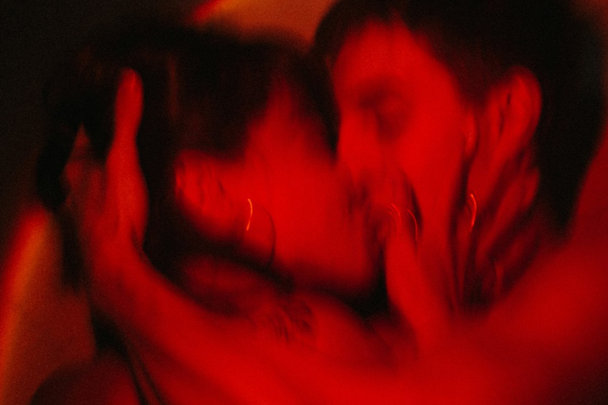 Blurred red-lit close-up of a couple kissing intimately