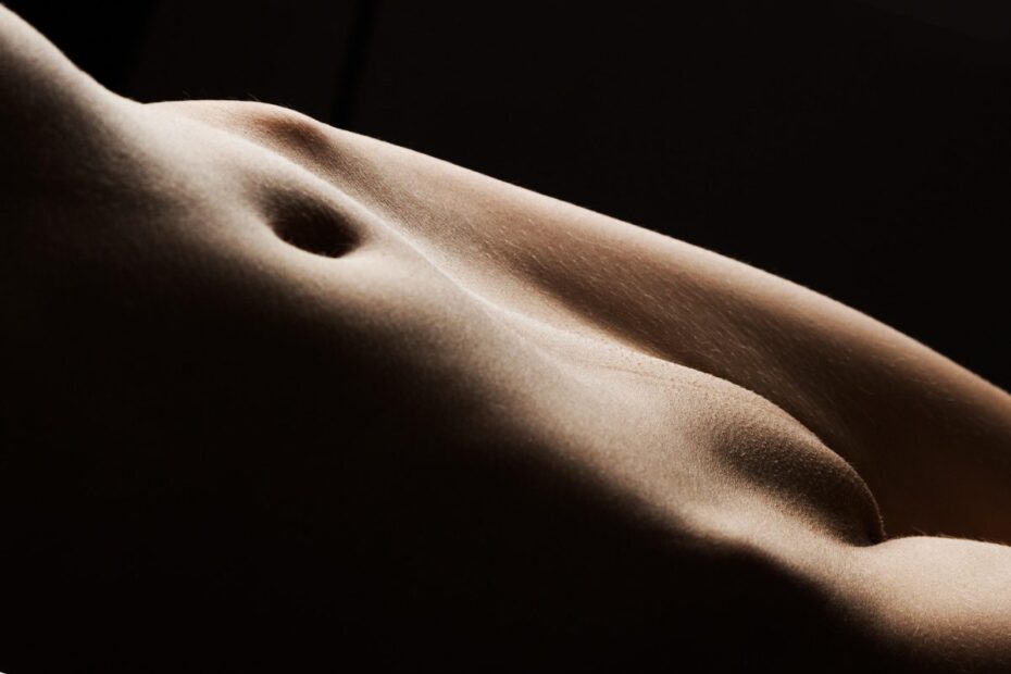 Artistic close-up of a nude torso and hip curve in warm light