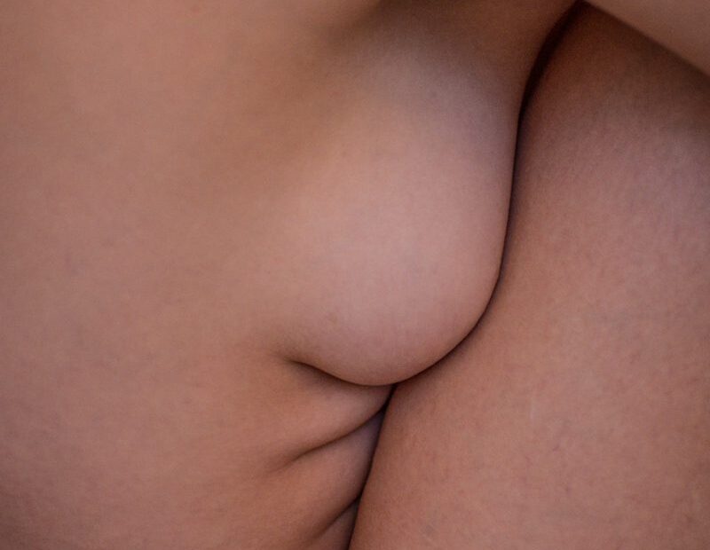 Soft-lit close-up of a nude woman's breast and torso curves