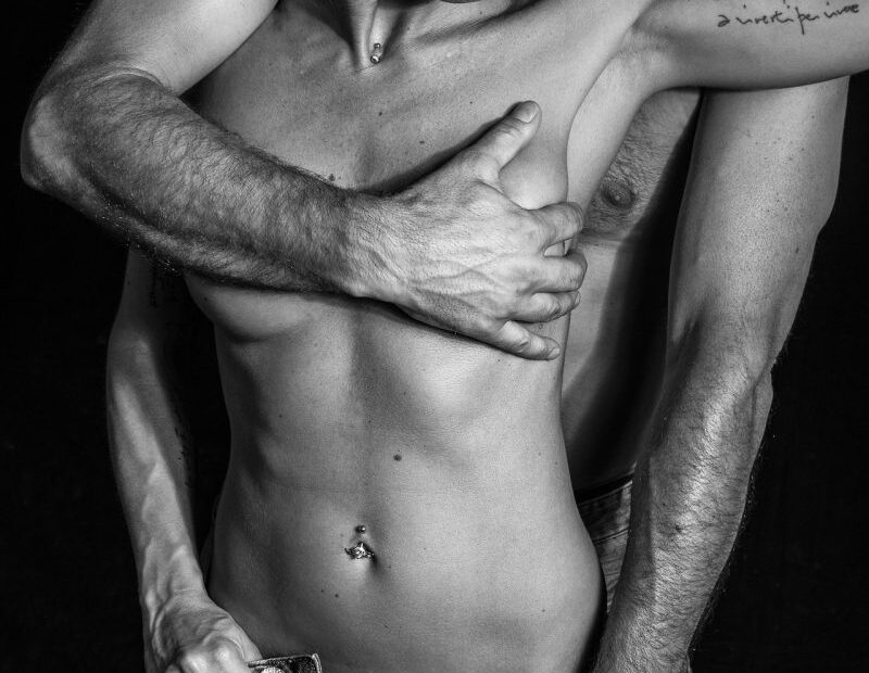 Black and white photo of a couple undressing in a passionate embrace