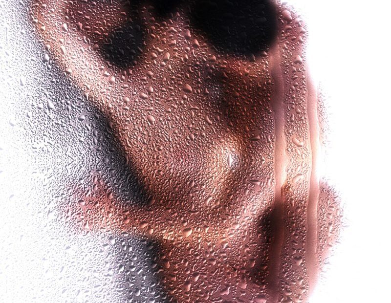 Nude figure seen through frosted, water-dropleted glass
