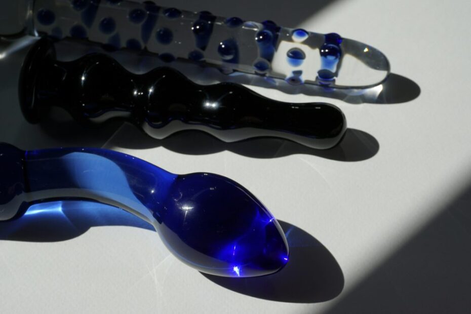 Three glass dildos in clear, black and blue arranged in sunlight