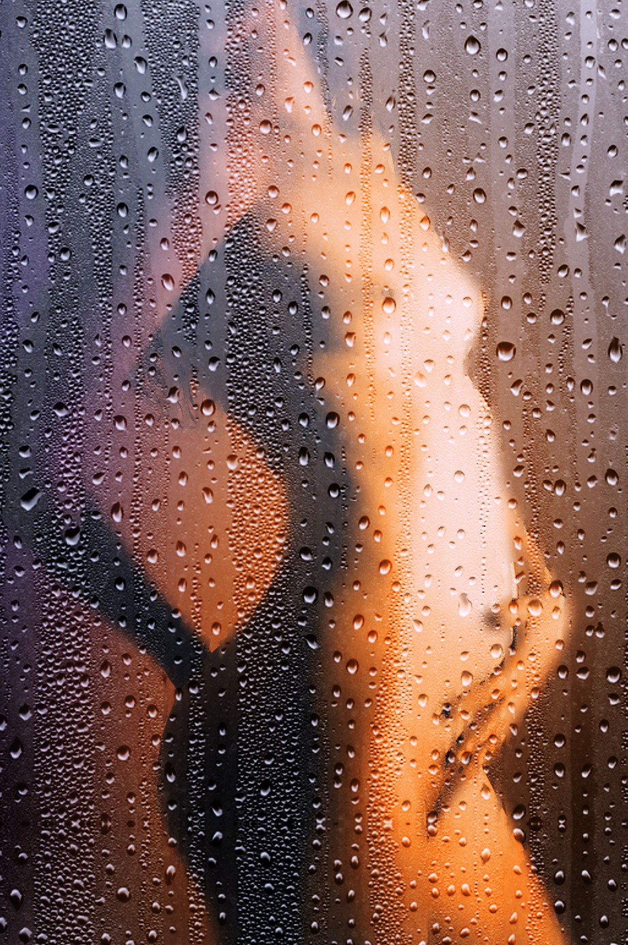 Silhouette of a nude woman behind a steamy, water-dropleted glass