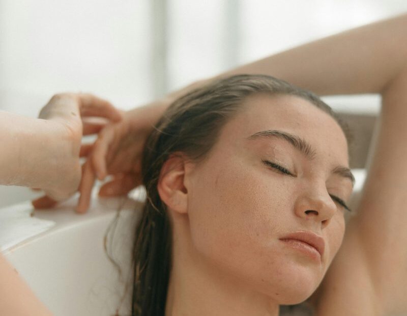 Woman relaxing with closed eyes in a milky flower-petal bath